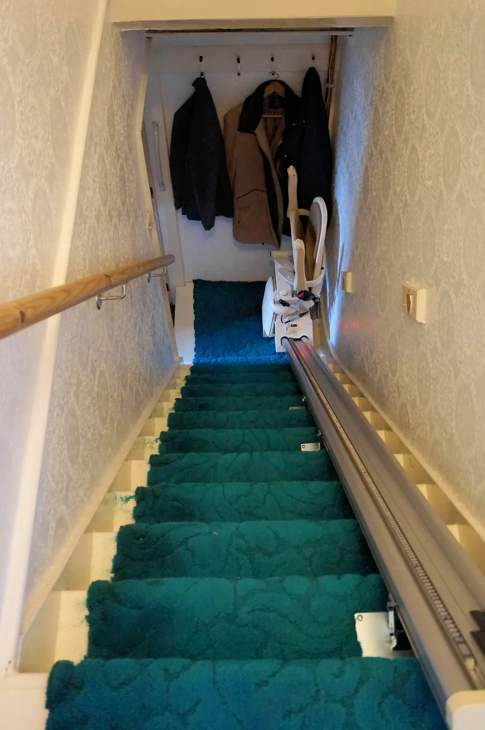 A stairlift installed on a straight staircase in a UK home, showing typical installation